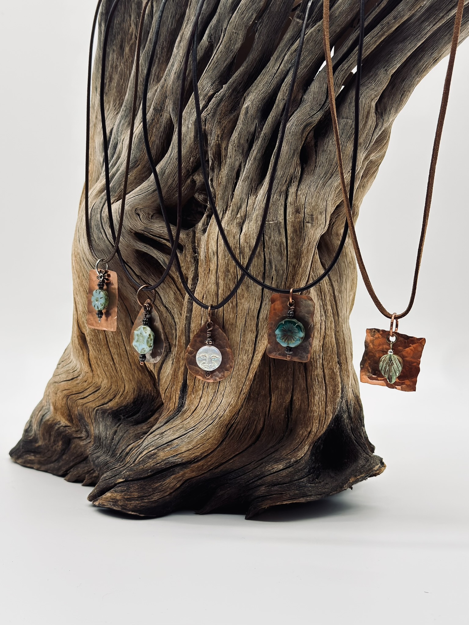 Five copper pendants on driftwood
