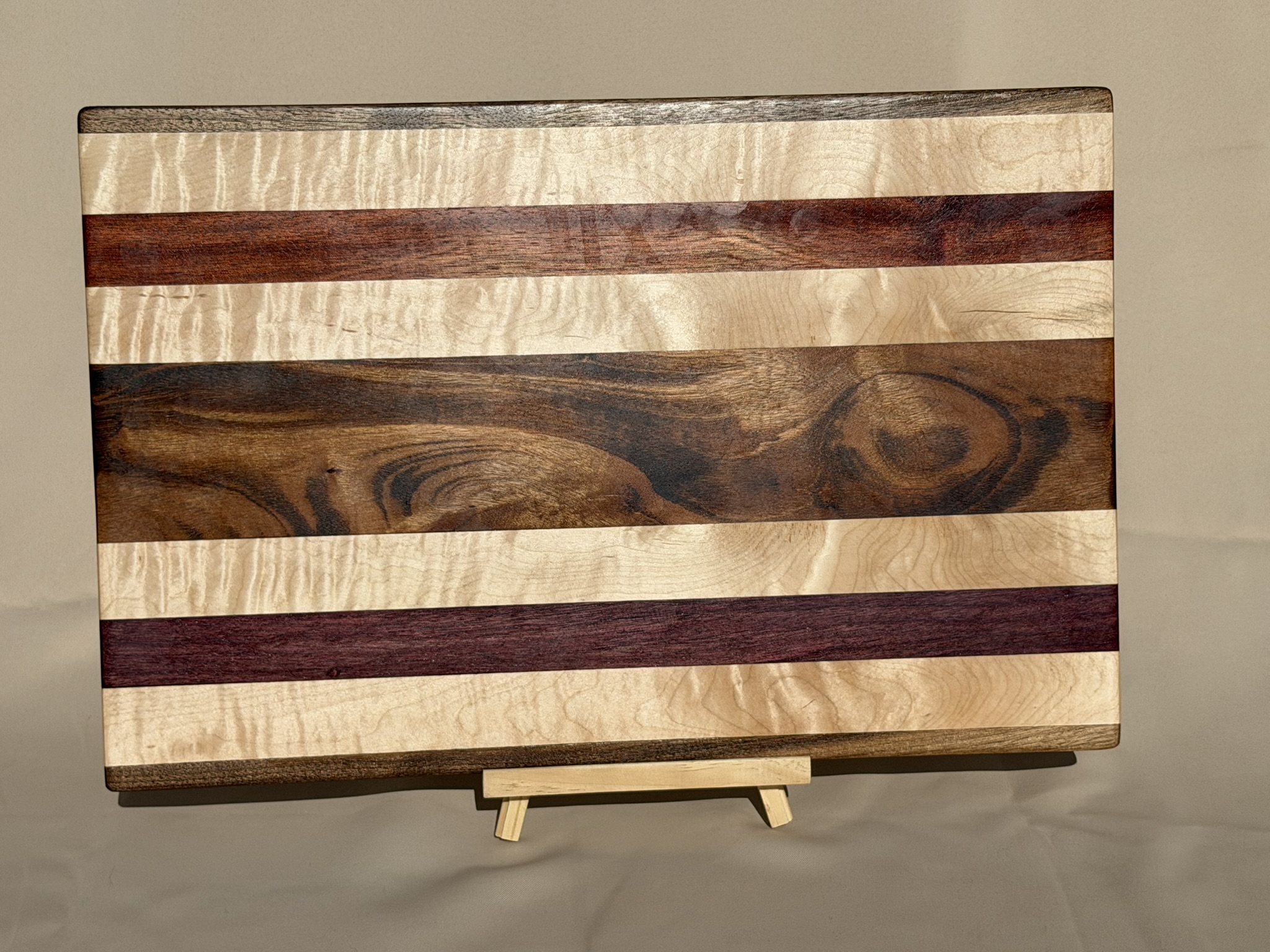 Striped hardwood cutting board on a black easel